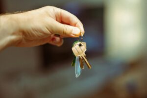 Une image en gros plan d'une main tenant un trousseau de clés avec plusieurs clés de maison, symbolisant l'immobilier et la propriété d'une maison.
