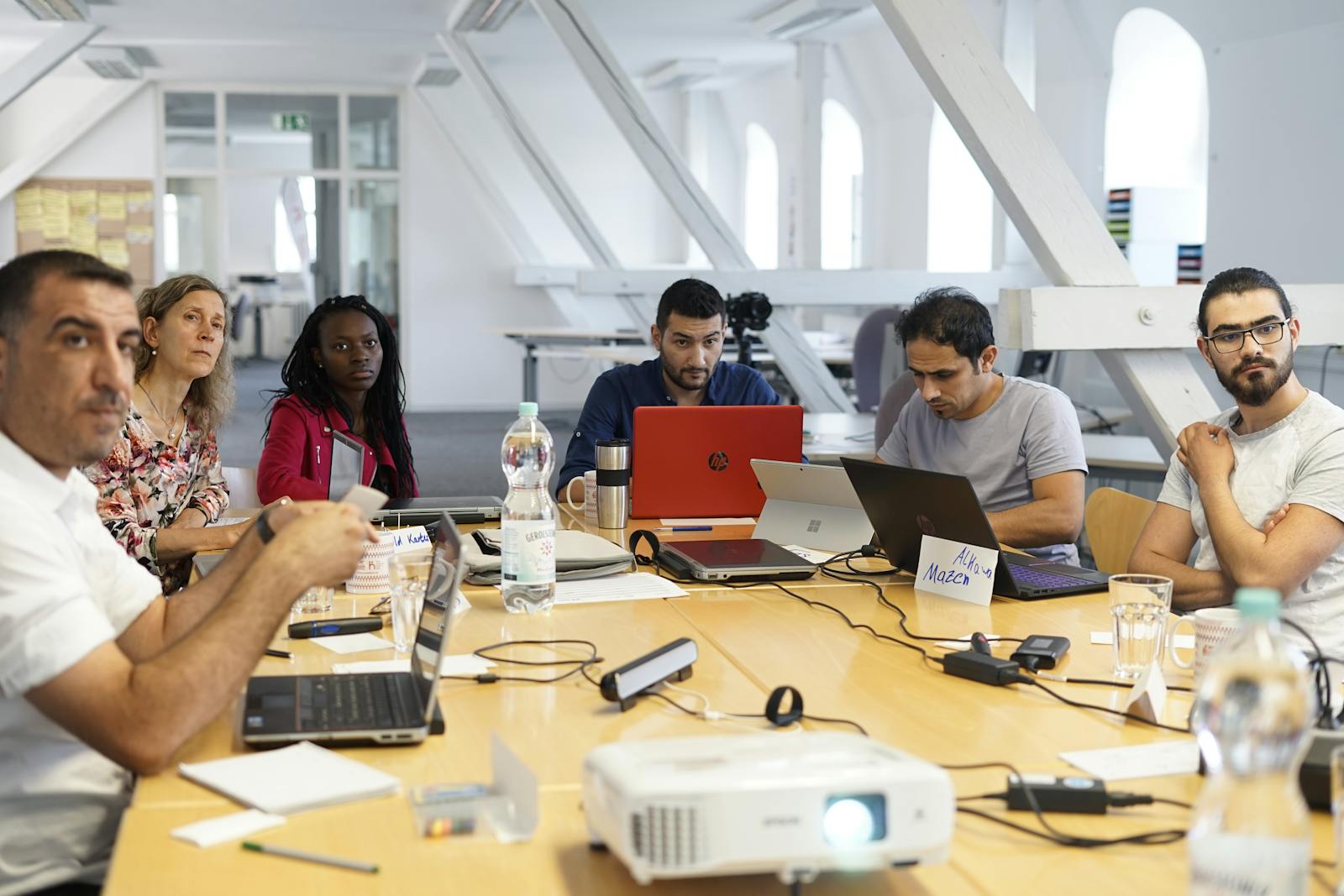 Diverse team collaborating around a conference table with laptops in a modern office setting.